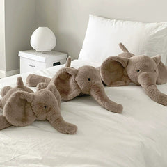 Three brown elephant plush toys of varying sizes on a bed, suggesting playful family-like togetherness.