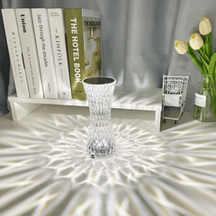 Water Ripple Aurora Decorative Lamp elegantly displayed on a desk among books and flowers, casting artistic light reflections around.