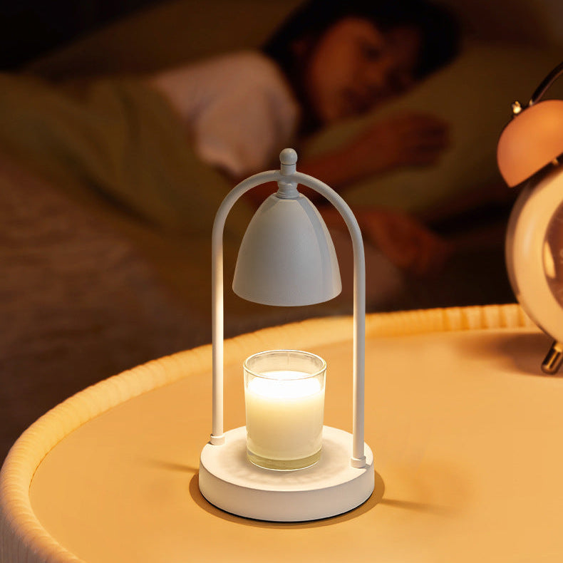 White candle warmer lamp lighting a candle on a bedside table, creating a peaceful mood for rest.
