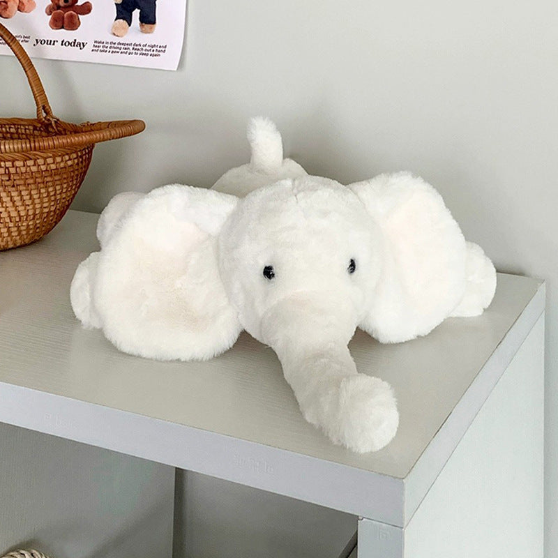 White elephant plush toy resting on a shelf in a minimalist room, adding a peaceful touch to the decor.