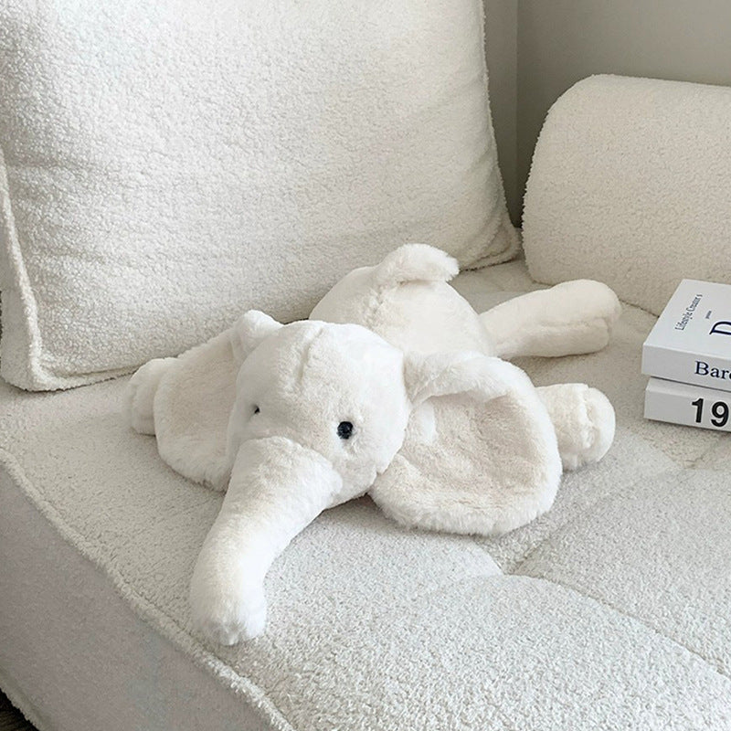 White elephant plush toy resting on a soft fabric sofa in a cozy setting, inviting gentle cuddling.